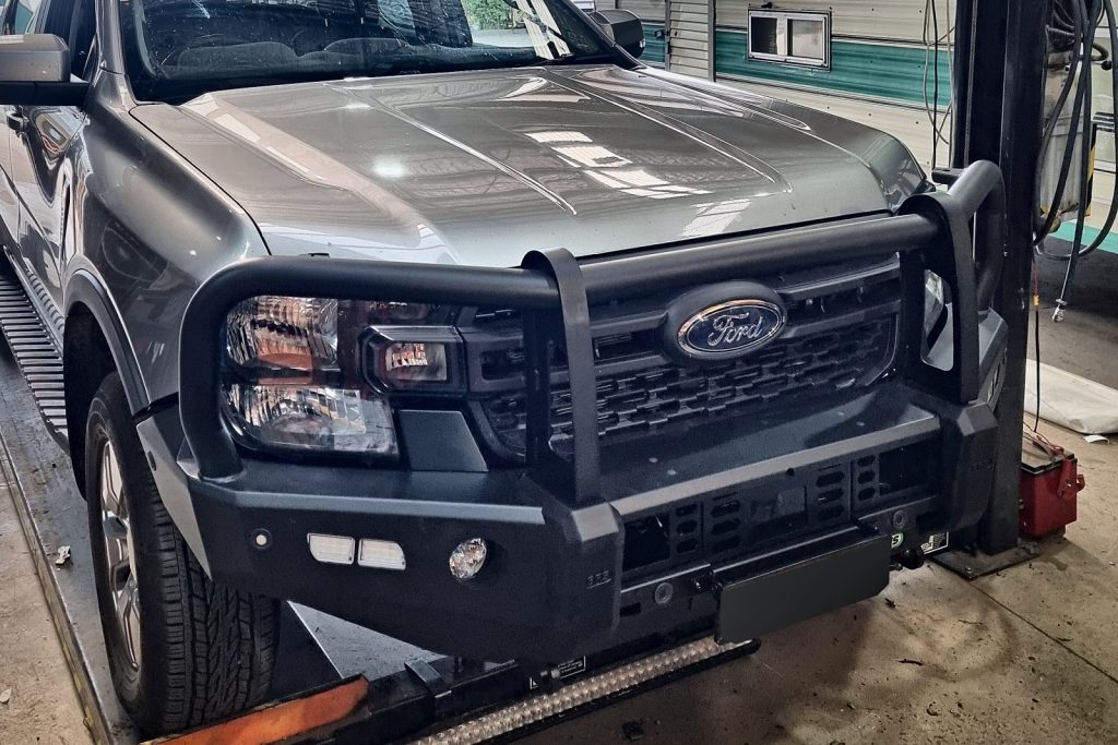 Grey Next-Gen Ford Ranger with a black EFS Stockman bull bar fitted, on the hoist in our Ballarat workshop.