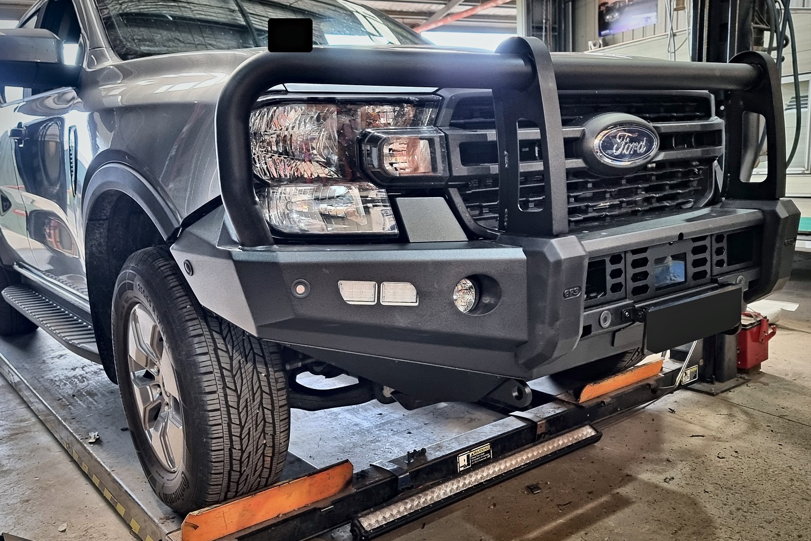 Side angle of the Ranger on the hoist showing the bull bar and front wheel.